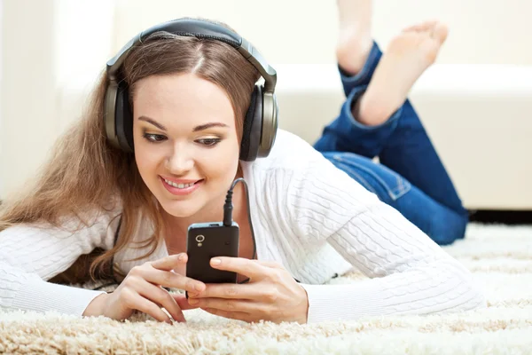 Femme couchée sur le tapis et écoutant de la musique — Photo