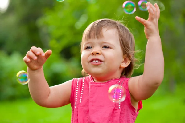 Malá holčička v parku s bublinami — Stock fotografie