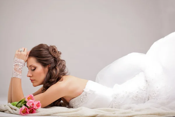 Studio photograph of a bride lying on the floor — Stock Photo, Image