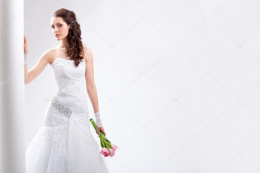 Beautiful bride standing near white column