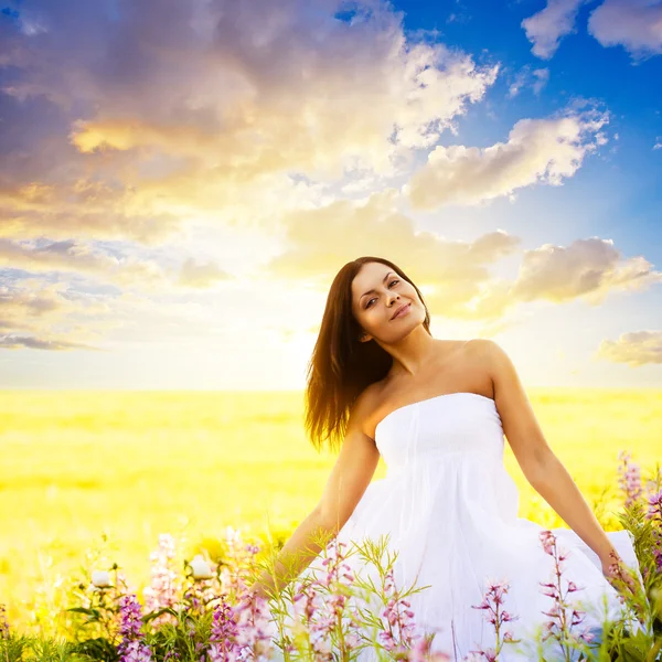 Vrouw lopen in een veld bij zonsondergang — Stockfoto