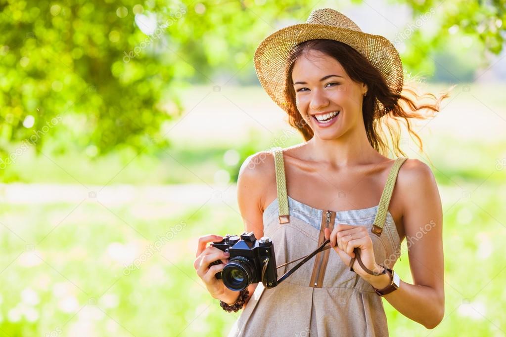 Happy young girl with camera outdoors