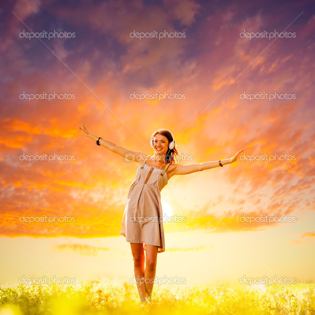 Girl wearing headphones walking on sunset — Stock Photo © chesterf