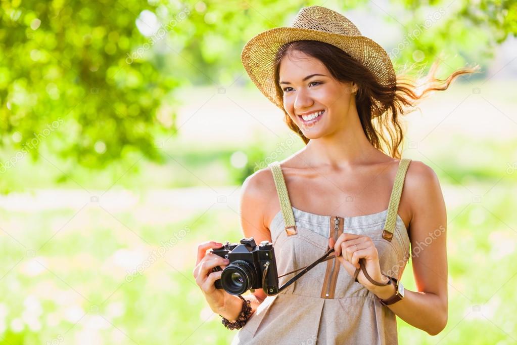 Happy young girl with camera outdoors