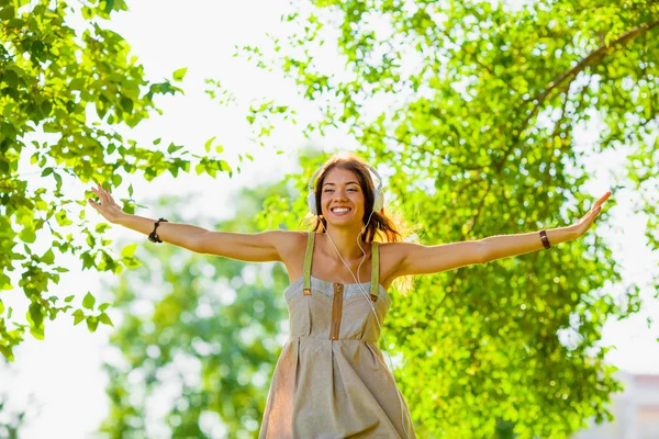 Glad tjej bär hedphones utomhus — Stockfoto
