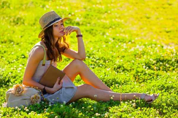 Chica con libro sentado en la hierba —  Fotos de Stock