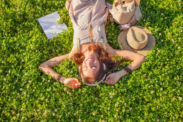 Женщина в наушниках лежит на траве — стоковое фото