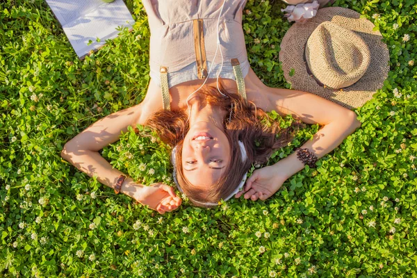 Mujer con auriculares tumbados en la hierba — Foto de Stock