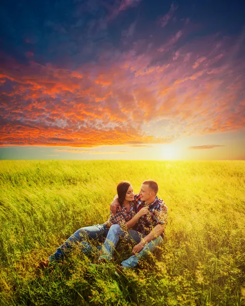 Pareja adulta joven sentada en el campo — Foto de Stock