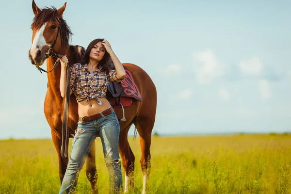 Beautiful woman standing near a horse — Stock Photo, Image
