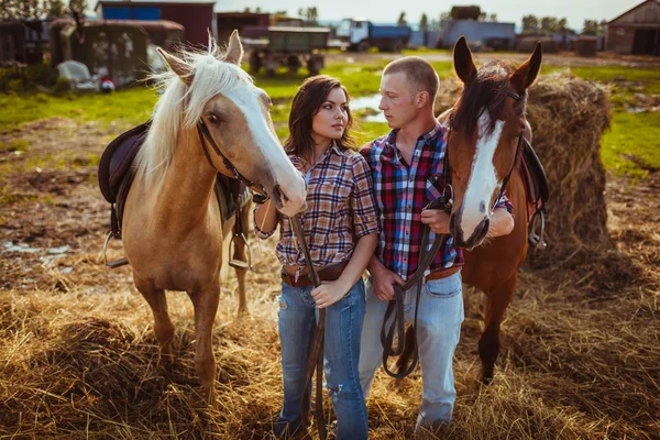 Пара стоящих на ферме с лошадьми — стоковое фото