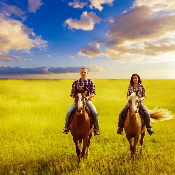 フィールド間で馬に乗ってカップル — ストック写真