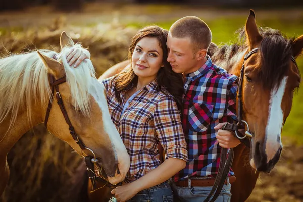 Couple debout à la ferme avec des chevaux — Photo