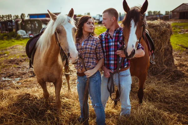 Couple debout à la ferme avec des chevaux — Photo