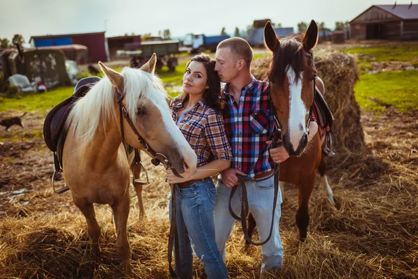 Pareja de pie en la granja con caballos —  Fotos de Stock