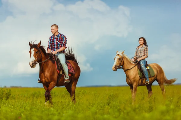 Pareja montando a caballo a través del campo — Foto de Stock