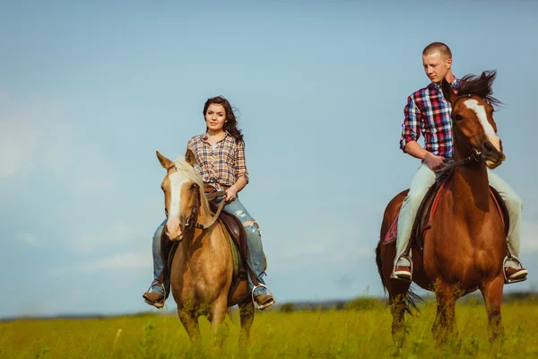 Paar rijden op paarden in het veld — Stockfoto