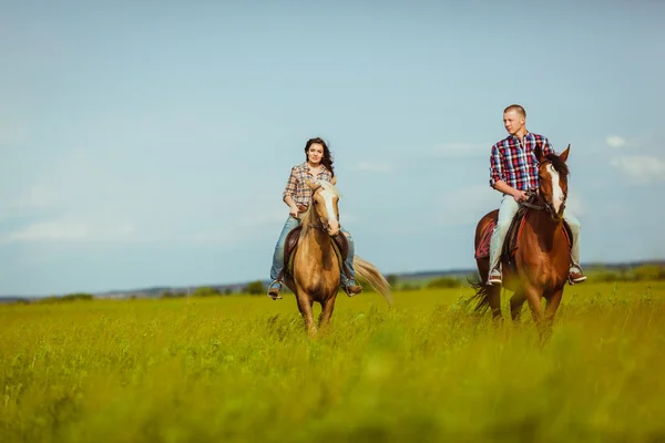 Pareja montando a caballo a través del campo — Foto de Stock