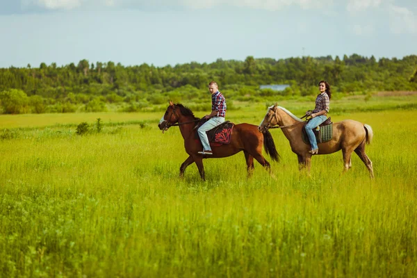 Coppia cavalcando su cavalli attraverso il campo — Foto Stock