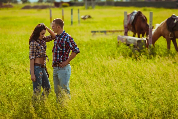 Pareja de pie en la granja con caballos — Foto de Stock