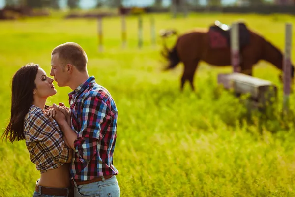 Couple standing on farm with horses — Stock Photo, Image