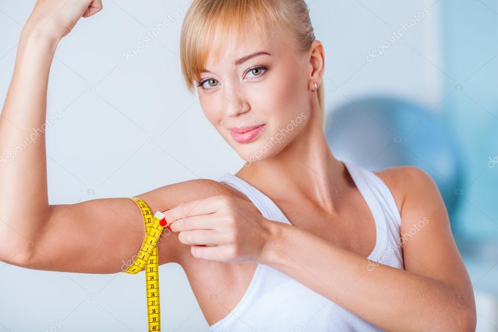 Blonde woman measuring biceps