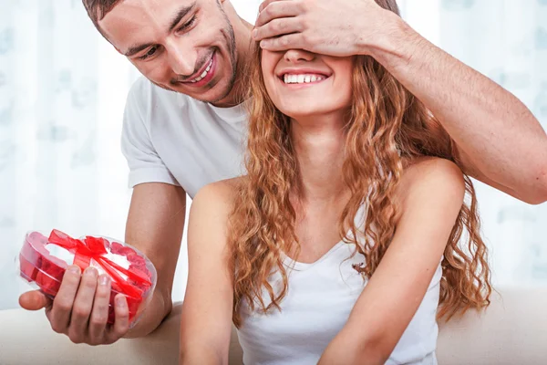 Young man gives her a heart shaped gift — Stock Photo, Image