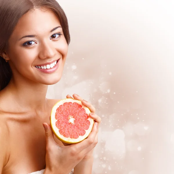 Beautiful woman holding half of grapefruit — Stock Photo, Image