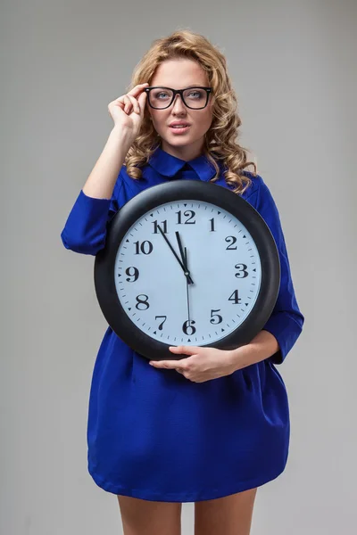 Kobieta nosi okulary, posiadający duży zegar — Zdjęcie stockowe