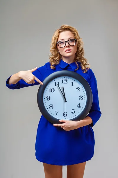 Woman wearing eyeglasses holding big clock — Stock Photo, Image