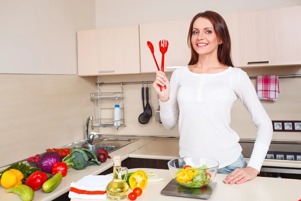 Lächelnde junge Hausfrau mixt frischen Salat — Stockfoto