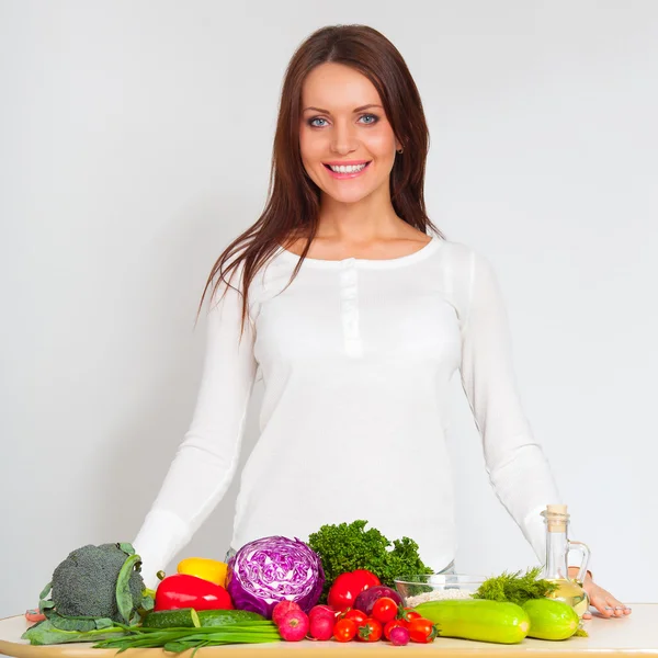 Glad ung kvinna med grönsaker i kök — Stockfoto