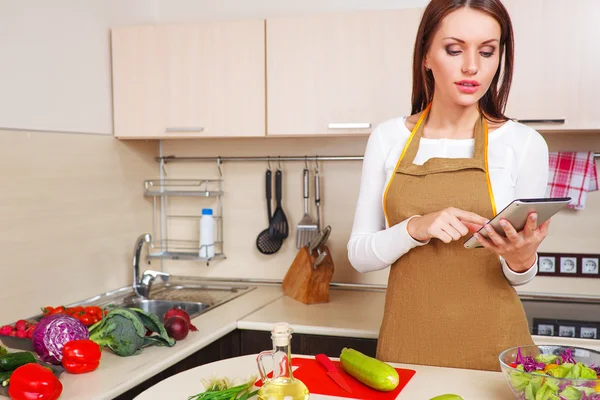 Mujer usando una tableta para cocinar en su cocina — Foto de Stock