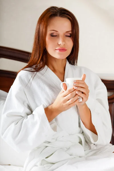 Lachende vrouw in slaapkamer drinken koffie op bed — Stockfoto