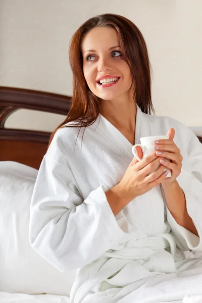Mujer sonriente en el dormitorio bebiendo café en la cama —  Fotos de Stock