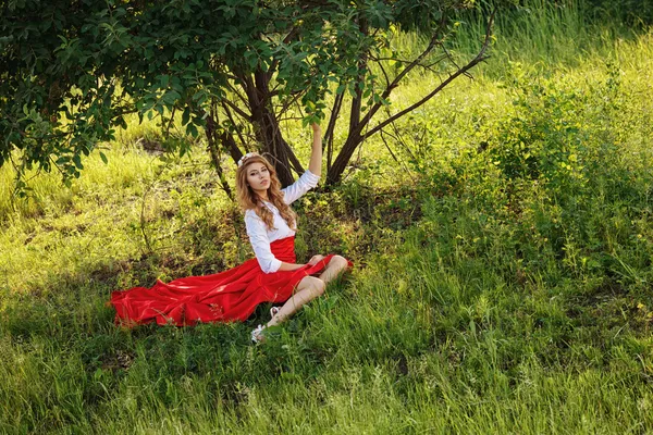 Portrait of blonde woman sitting under the tree — Stockfoto