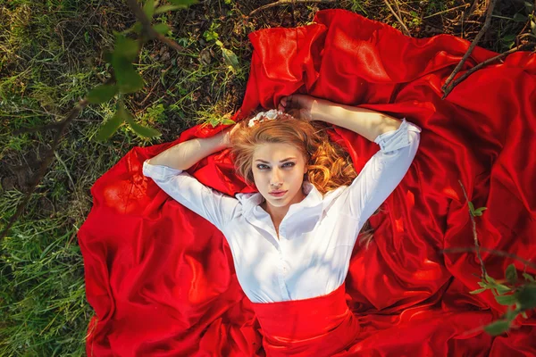 Frau im roten Rock unter dem Baum liegend — Stockfoto