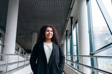 Geçiş bölgesinde genç bir kadın pencereye bakıyor ve gülümsüyor.