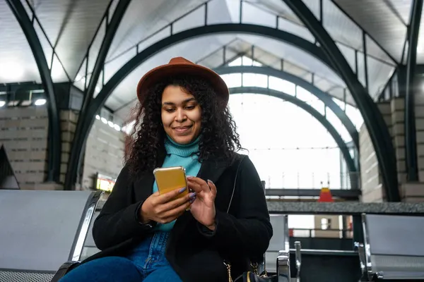 Kvinna Sitter Avgångsområdet Och Håller Smartphone — Stockfoto