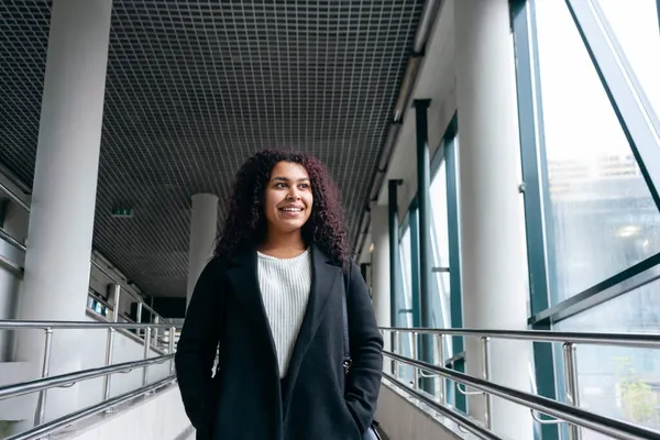 Geçiş bölgesinde genç bir kadın pencereye bakıyor ve gülümsüyor.