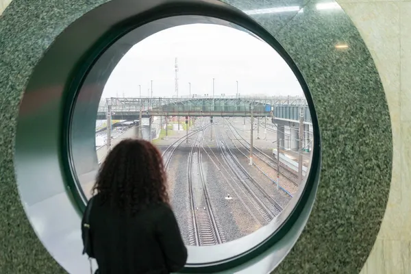 Mulher Vista Para Trás Olhando Para Ferrovia Através Janela Redonda Imagem De Stock