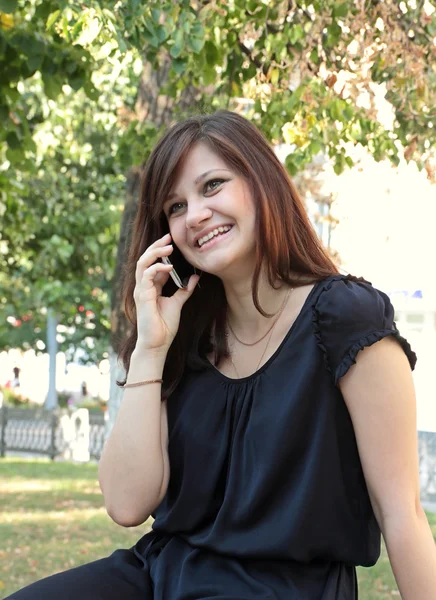 Menina bonita chamada por telefone em um parque — Fotografia de Stock