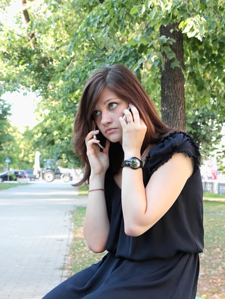 Dívka mluví o dvou mobilních telefonů — Stock fotografie