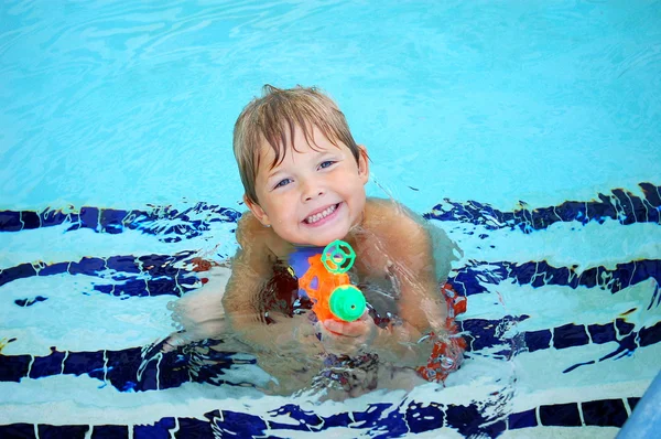 Jongen met zeer blauwe ogen en een oranje squirt gun — Stockfoto