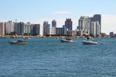 Miami Beach, Florida 'da Biscayne Körfezi' nin batı kıyısındaki yüksek binalar körfeze demirlemiş yelkenlilere bakıyor.,
