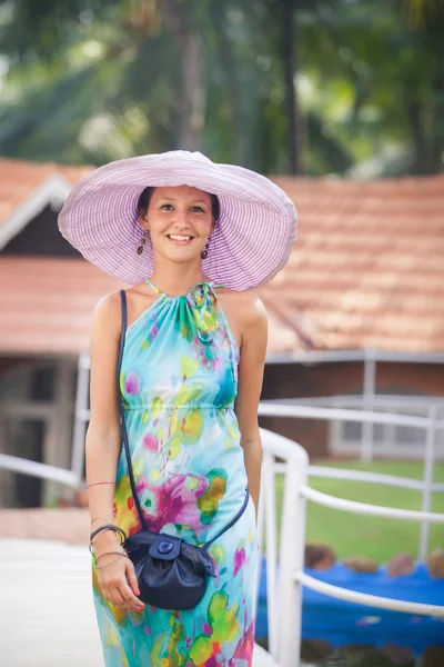 Menina morena em vestido de flor e chapéu rosa — Fotografia de Stock