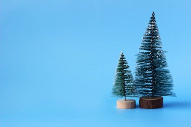 Mavi arka planda iki yapay Noel ağacı, yazı için bir yer. Yeni yıl kavramı