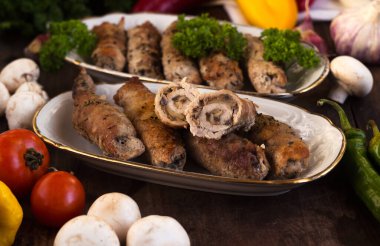 Mantarlı domuz eti, yeşillik ve sebzelerle çevrili et ruloları. Ukrayna yemeklerine krucheniki denir.
