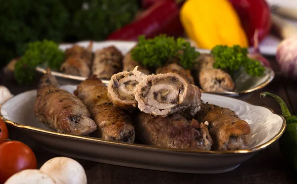 Pork rolls with mushrooms, meat rolls surrounded by greenery and vegetables. Ukrainian dishes is called krucheniki
