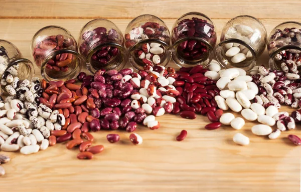 テーブルの上の瓶から多色の豆が注ぎ出されます 色の豆 — ストック写真
